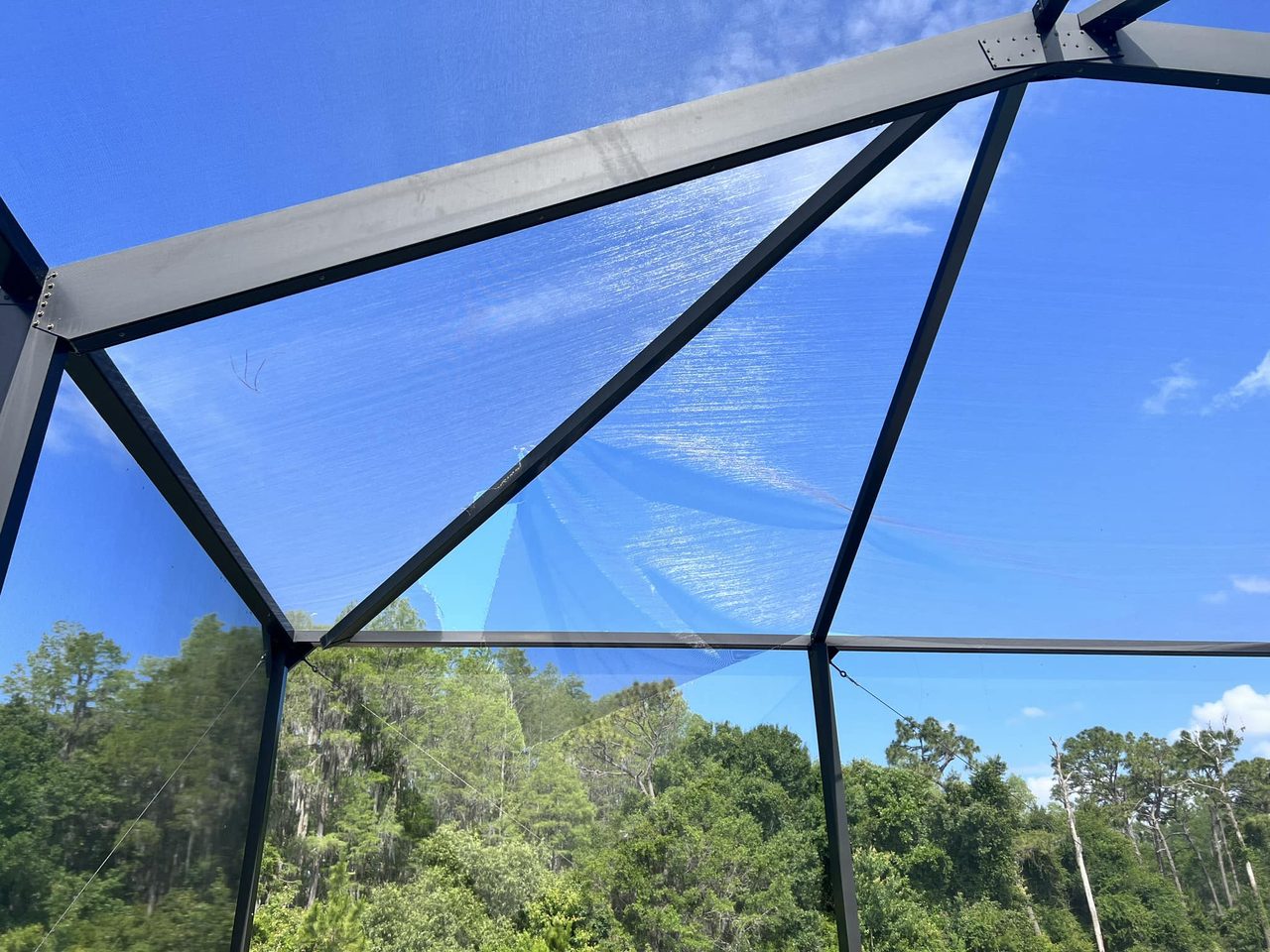Close-up of damaged pool cage screen panel and aluminum frame — Tampa Bay structural assessment